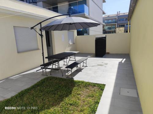 a patio with a table and chairs and an umbrella at Beach house for 4 by the sea in Gafanha da Nazaré