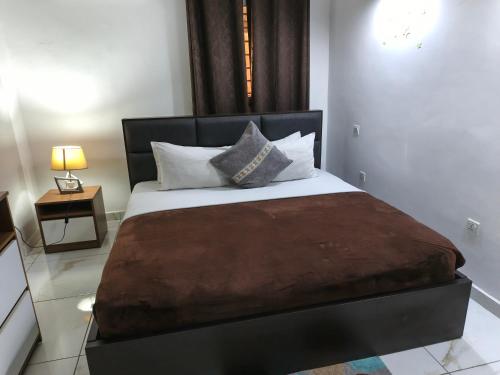 a bedroom with a large bed with a brown blanket at Accra City Studios & Apartment in Accra