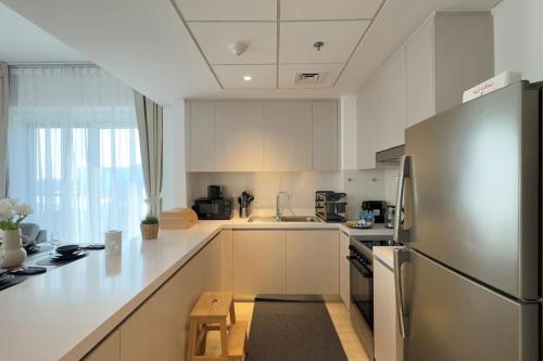 a kitchen with white cabinets and a stainless steel refrigerator at Elegant 4BR - Stylish Pearl Edge Escape in Abu Dhabi
