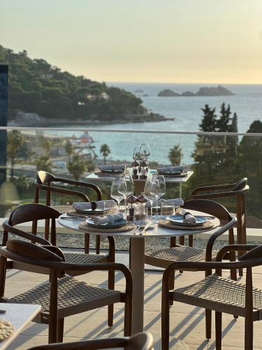 a table with wine glasses and chairs on a balcony at Hotel Sumratin in Dubrovnik