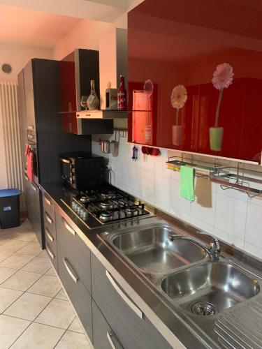 a kitchen with a stainless steel sink and red cabinets at Tana per gli ospiti in Terni