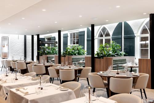a restaurant with white tables and chairs and plants at Kasteel Steenenburg in Den Bosch