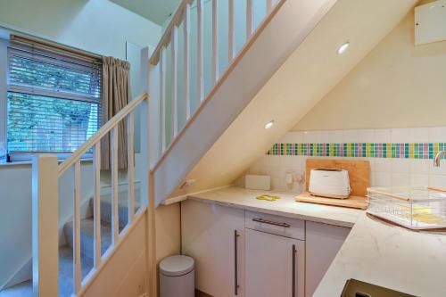 a kitchen with white cabinets and a staircase at Finest Retreats - Upper Deck in Cawsand