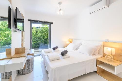 a white bedroom with two beds and a desk at La Casa Del Rio in Kymi