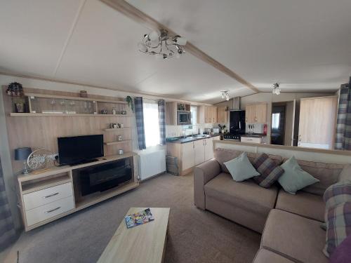 a living room with a couch and a kitchen at Orchid by Davies Caravans on Oakdene Forest Park in Saint Leonards