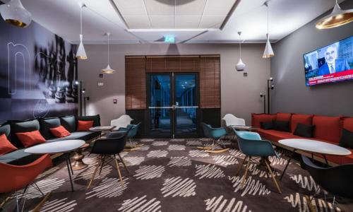 a waiting room with couches and tables and chairs at Noxi Hotel in Sétif