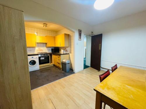 a kitchen with yellow cabinets and a table in a room at Budget Stay In Luton 02 02 in Luton