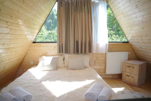 a large bed in a wooden room with a large window at your dream cottage in Ts'ikhisdziri