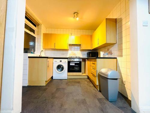 a kitchen with yellow cabinets and a washer and dryer at Budget Stay In Luton 02 02 in Luton