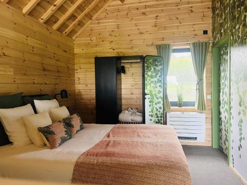 a bedroom with a bed and a wooden wall at Les pavillons de La Libellule in Beauraing