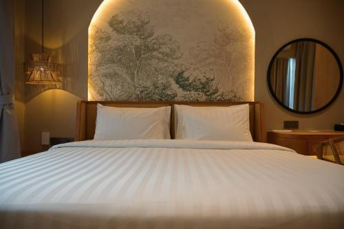 a bedroom with a large bed with white sheets at Hygge Hotel and Villas Seminyak in Seminyak