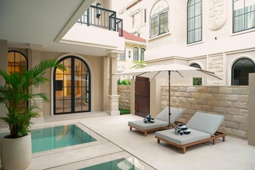 a patio with two chairs and an umbrella next to a pool at Hygge Hotel and Villas Seminyak in Seminyak