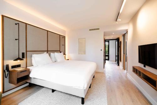 a bedroom with a large white bed and a flat screen tv at Kasteel Steenenburg in Den Bosch