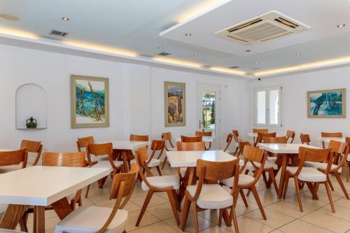 a dining room with white tables and chairs at Pyrgaki Hotel in Parikia