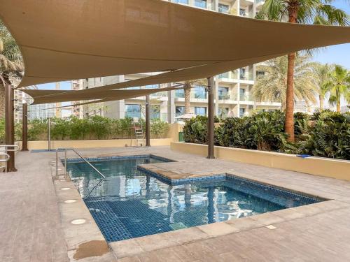 una piscina con un ombrellone davanti a un edificio di FIRST CLASS Studio Cozy Elegance a Dubai