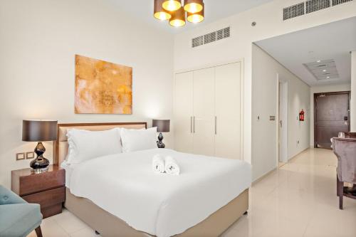 una camera da letto con un grande letto bianco con due asciugamani sopra di FIRST CLASS Studio Cozy Elegance a Dubai