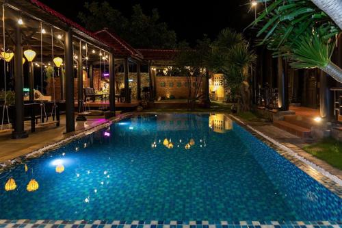a swimming pool in a resort at night at Sabina Boutique Hotel & Villa Mui Ne in Mui Ne