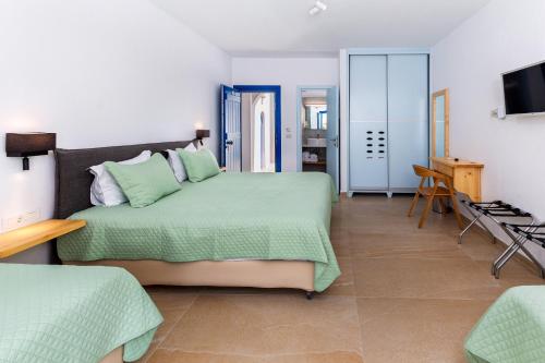 a bedroom with a green bed and a television at Pyrgaki Hotel in Parikia