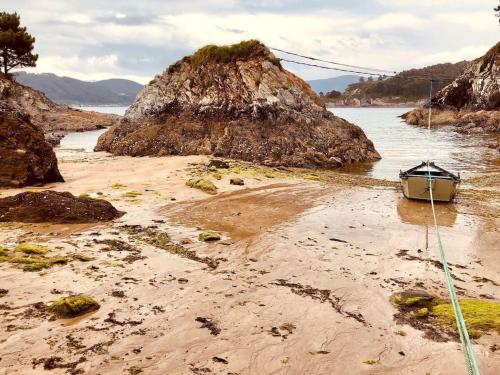 a boat sitting on a beach near the water at The Cliffs - Cala Porto do Val in O Vicedo