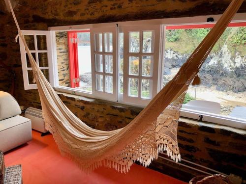 a hammock hanging in a room with windows at The Cliffs - Cala Porto do Val in O Vicedo