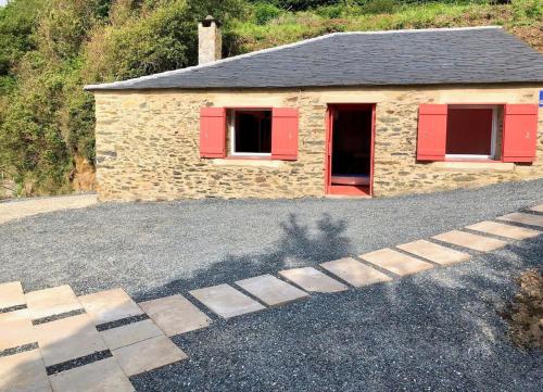 a stone building with red shutters on a driveway at The Cliffs - Cala Porto do Val in O Vicedo