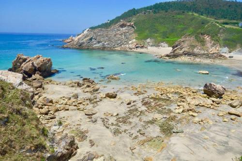 a beach with rocks and the blue ocean at The Cliffs - Cala Porto do Val in O Vicedo