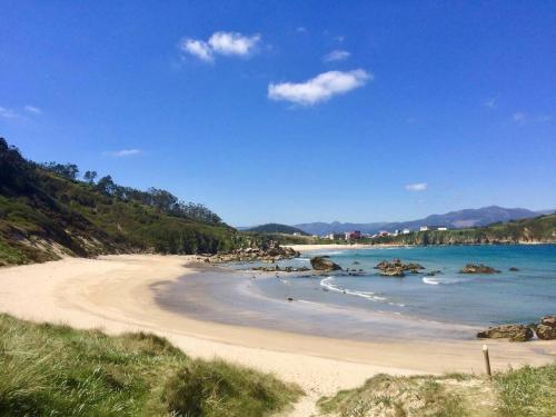a sandy beach with rocks in the water at The Cliffs - Cala Porto do Val in O Vicedo