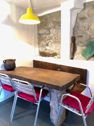 a wooden table with two red chairs and a yellow lamp at OBarqueiro - El descanso del Peregrino in O Barqueiro