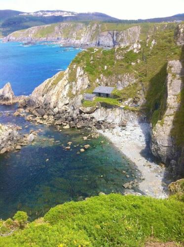 a house on a cliff next to the ocean at OBarqueiro - El descanso del Peregrino in O Barqueiro