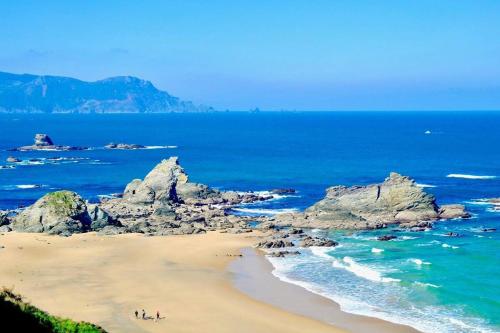 people on a beach with rocks in the ocean at OBarqueiro - El descanso del Peregrino in O Barqueiro