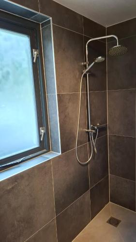 a shower in a bathroom with a window at Groene heuvels 101 in Ewijk