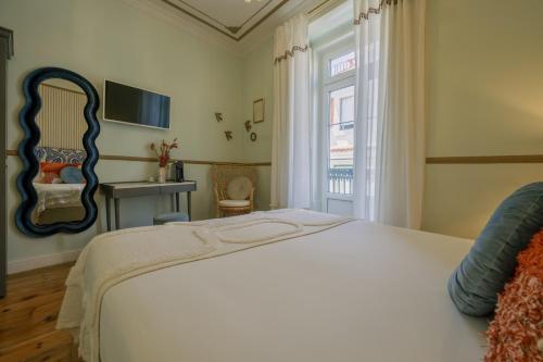 a bedroom with a bed with a mirror and a window at Solar dos Poetas in Lisbon