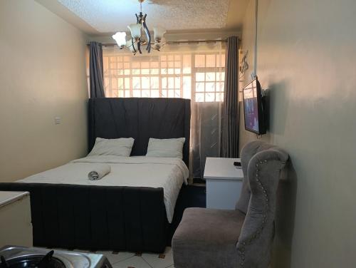 a bedroom with a bed and a chair and a window at Zuri studio in Kinoo