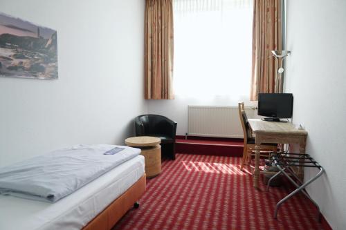 a bedroom with a bed and a desk with a computer at B&K Hotels in Vlotho