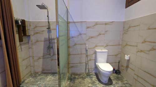 a bathroom with a toilet and a glass shower stall at Lagoon gate Tangalle Resort in Tangalle