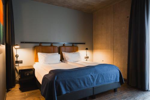 a bedroom with a bed with a blue blanket on it at Exeter Hotel in Reykjavík