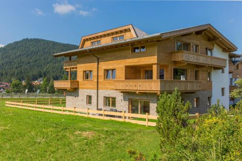 a large wooden house with a fence in a field at Princess Bergfrieden in Seefeld in Tirol
