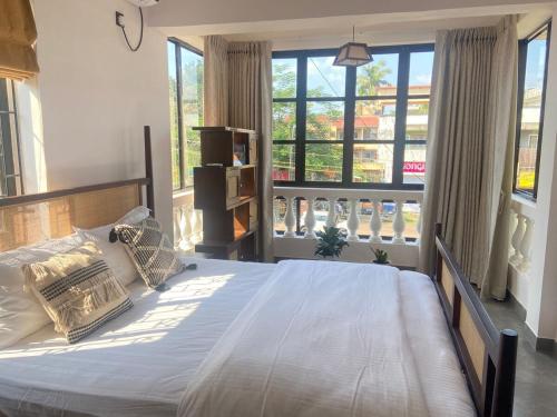 a bedroom with a large bed and large windows at Aesthetic Apartment in NorthGoa in Siolim