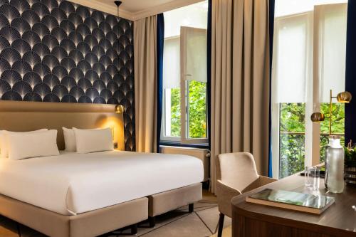 a hotel room with a bed and a desk and a table at Hotel The Augustin in Brussels