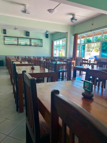 een eetkamer met houten tafels, stoelen en ramen bij Le Paradisier Hotel Restaurant in Antsohihy