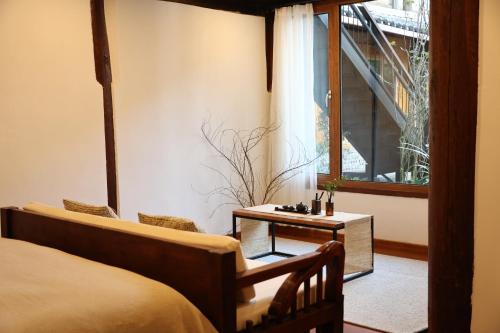 a bedroom with a bed and a table and a window at Lijiang Sadhu Inn in Lijiang