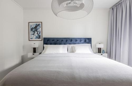 a white bedroom with a large bed and a chandelier at Villa with lakeside location in Dvärsätt