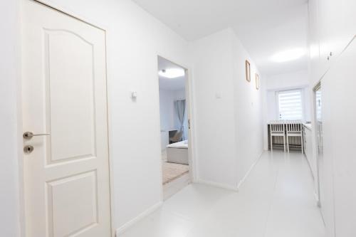 a white hallway with a door and a mirror at Lun Apartment in Cluj-Napoca
