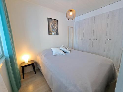 Un dormitorio con una cama y una lámpara sobre una mesa. en Aurinkohiekka A1, en Kalajoki