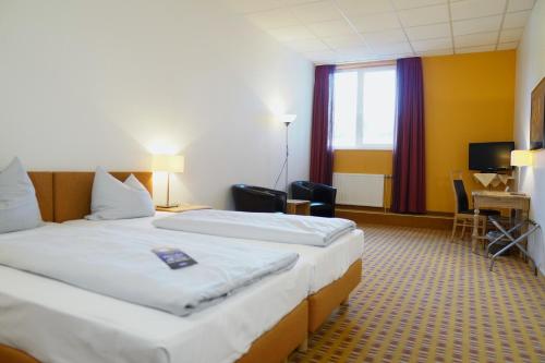 a hotel room with two beds and a desk at B&K Hotels in Vlotho