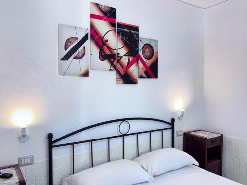 a bedroom with a bed with four pictures on the wall at Villa Julien Quartu Sant'Elena Sardegna in Santa Luria