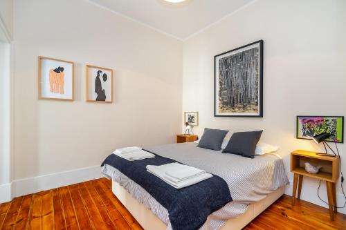 Un dormitorio blanco con una cama y algunas fotos en la pared en Lisbon Design Flat, Luxury, 7 People, Pool Garden, en Lisboa