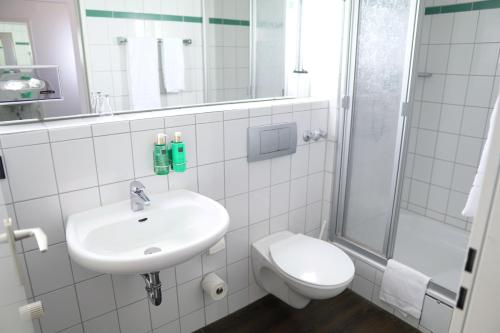 a bathroom with a sink and a toilet and a shower at B&K Hotels in Vlotho