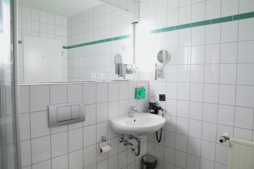 a white bathroom with a sink and a mirror at B&K Hotels in Vlotho