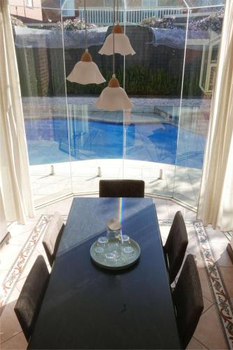 a dining room table with chairs and a view of a pool at Fantastic Family Home with Pool at Concord in Sydney